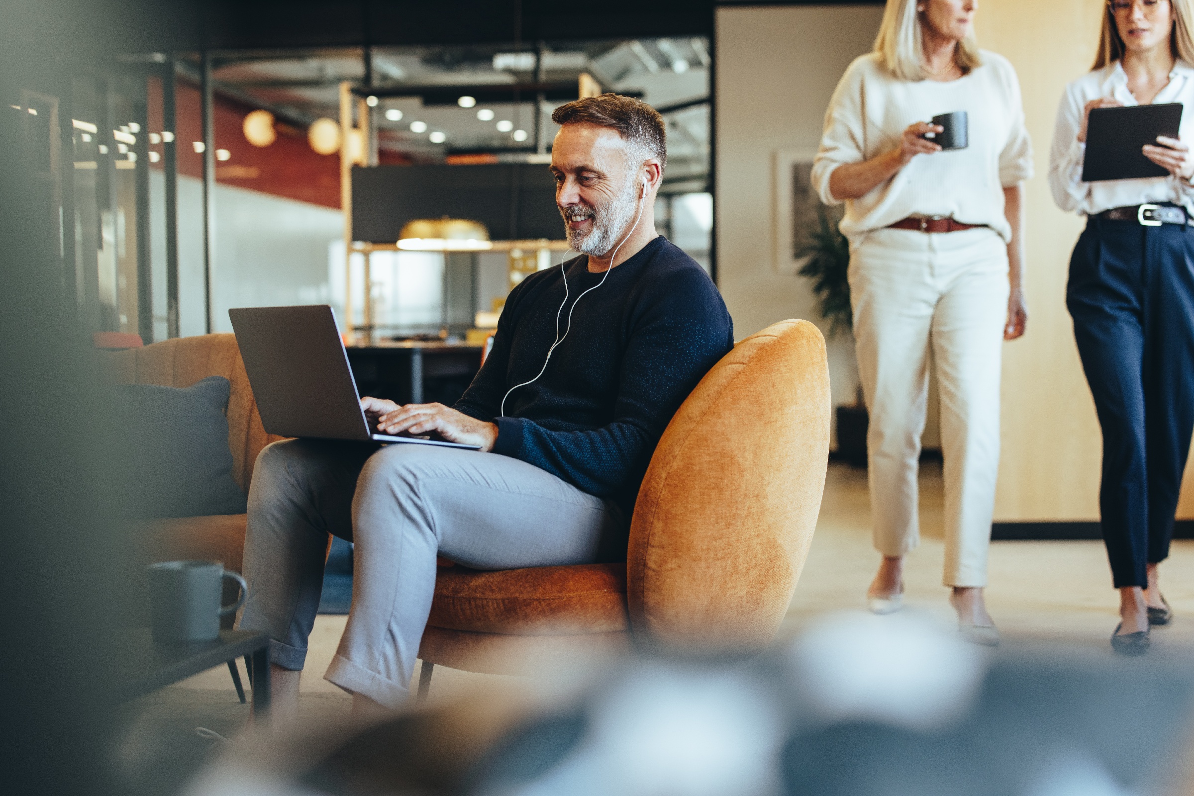 An employee attends an online meeting while two co-workers walk by.